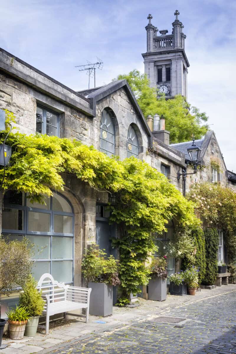 Exterior of a historic stone building with climbing plants and a white bench in Edinburgh Old Town. at St Christopher's Edinburgh Old Town hostel