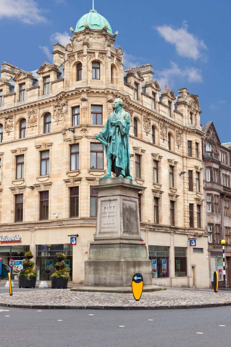 Statue of a historical figure on a pedestal in front of a historic building with a green dome. at St Christopher's Edinburgh Old Town hostel