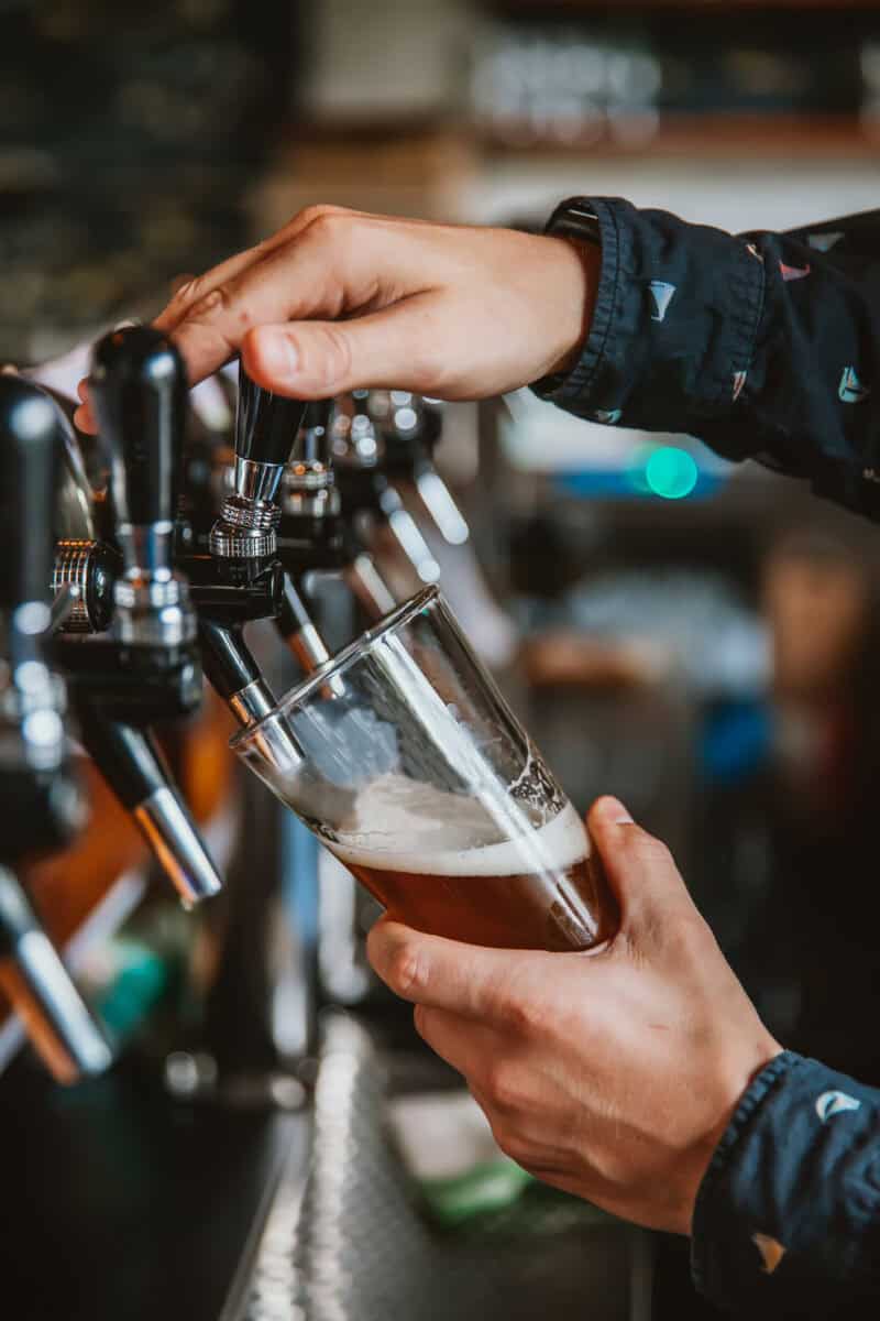 Bar staff pouring beer from tap with stone wall background. at St Christopher's Edinburgh Old Town hostel