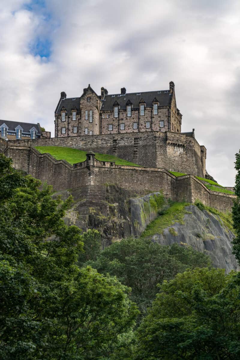 View of Edinburgh Castle on the hill with stone walls and greenery in the foreground. at St Christopher's Edinburgh Old Town hostel