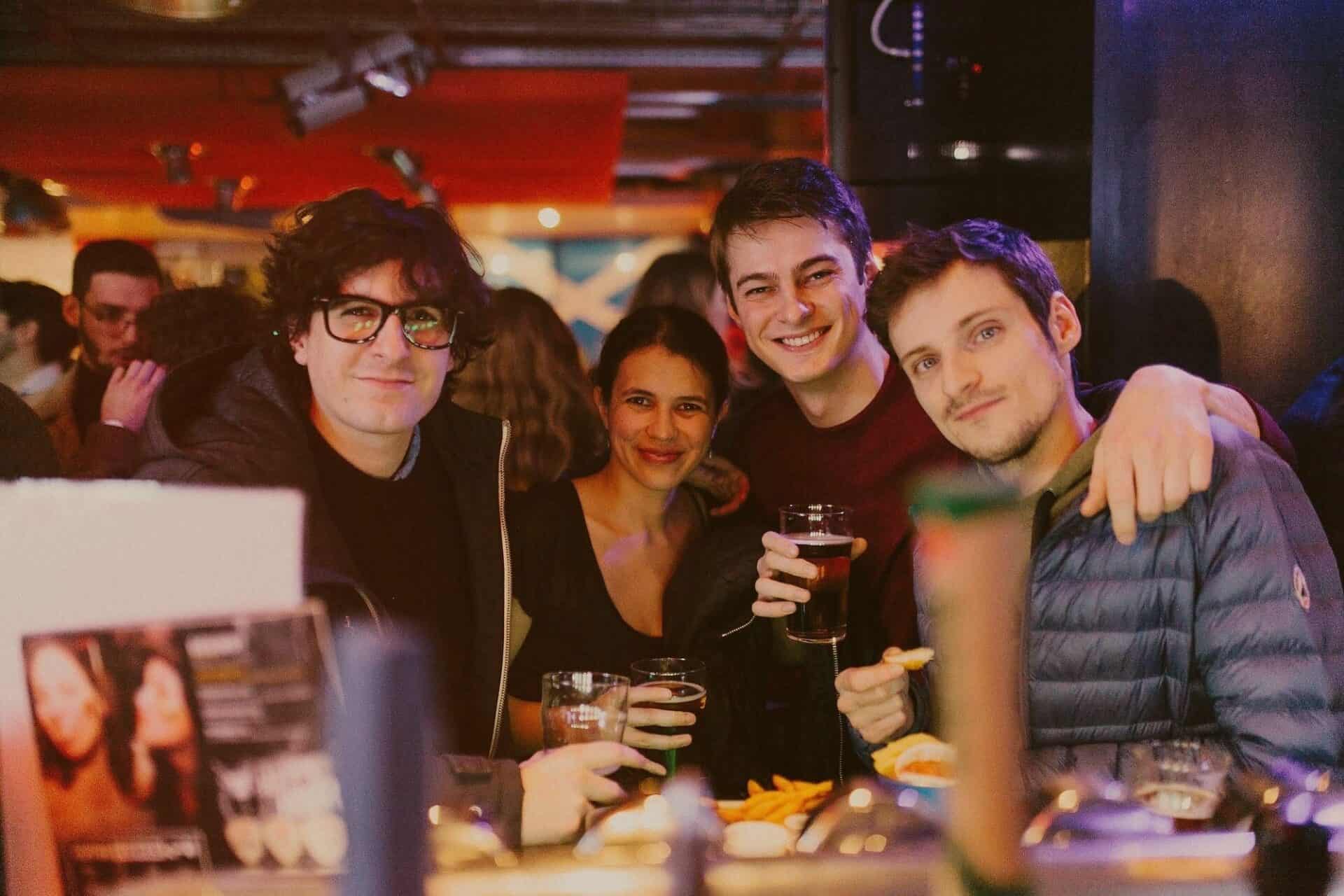 People enjoying drinks at Belushi's bar with colourful lighting and a lively atmosphere. at St Christopher's Edinburgh Old Town hostel