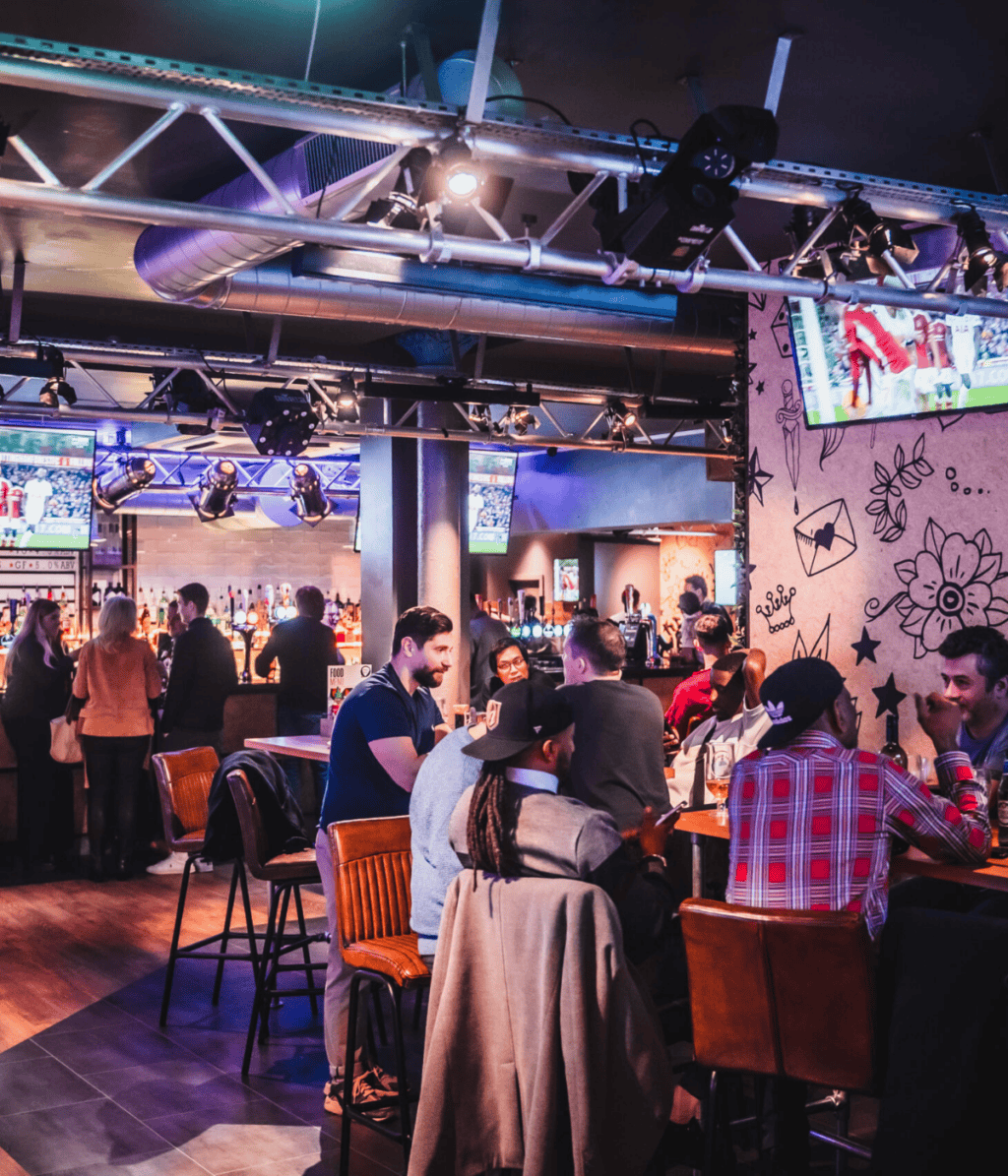 Brightly lit bar with multiple screens and lively atmosphere.