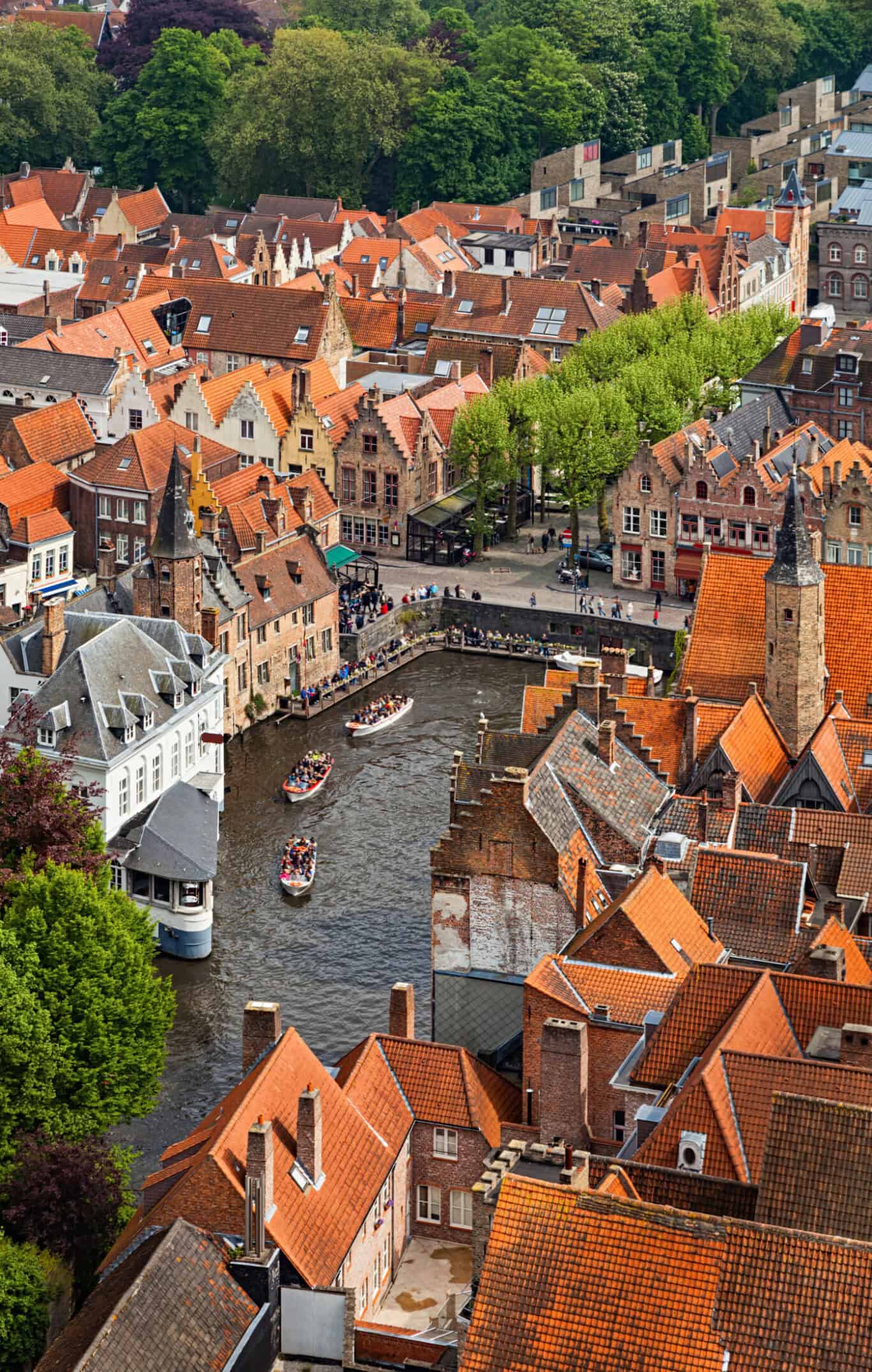 Aerial view of a European town with red-tiled roofs and a canal with boats.