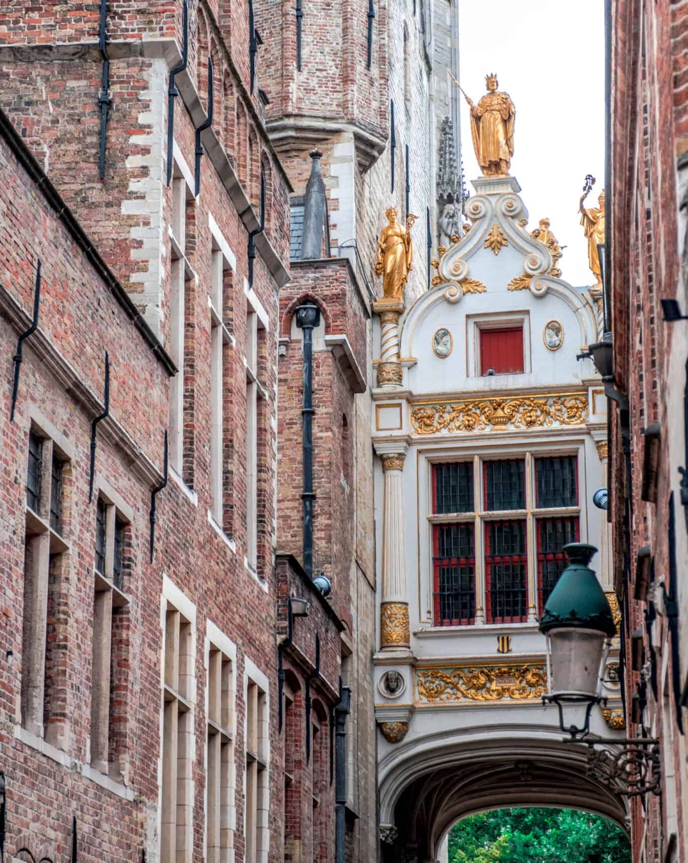 Narrow street with historic brick buildings and ornate archway with gold accents.