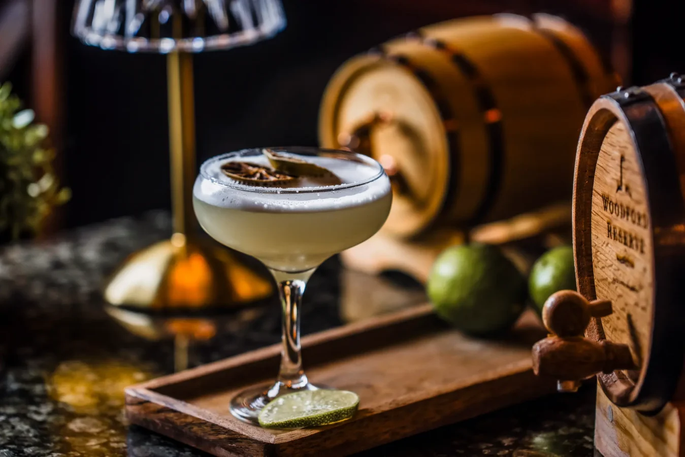 A foamy cocktail in a coupe glass on a wooden tray at The Hercules Pillars, Holborn