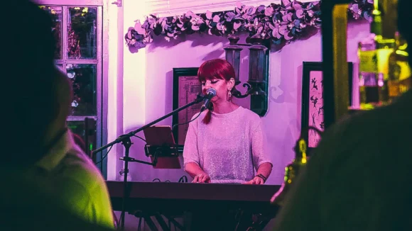 A solo singer performing live on stage at St Christopher's Pub on Borough High Street, London Bridge, to a seated crowd