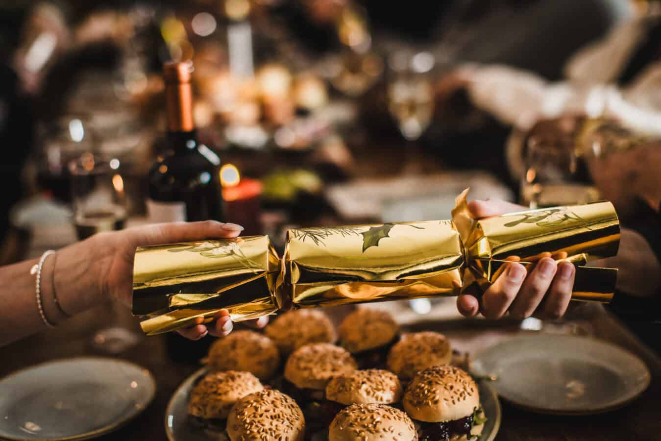 Person holding a gold-wrapped Christmas cracker at St Christopher's Pub.