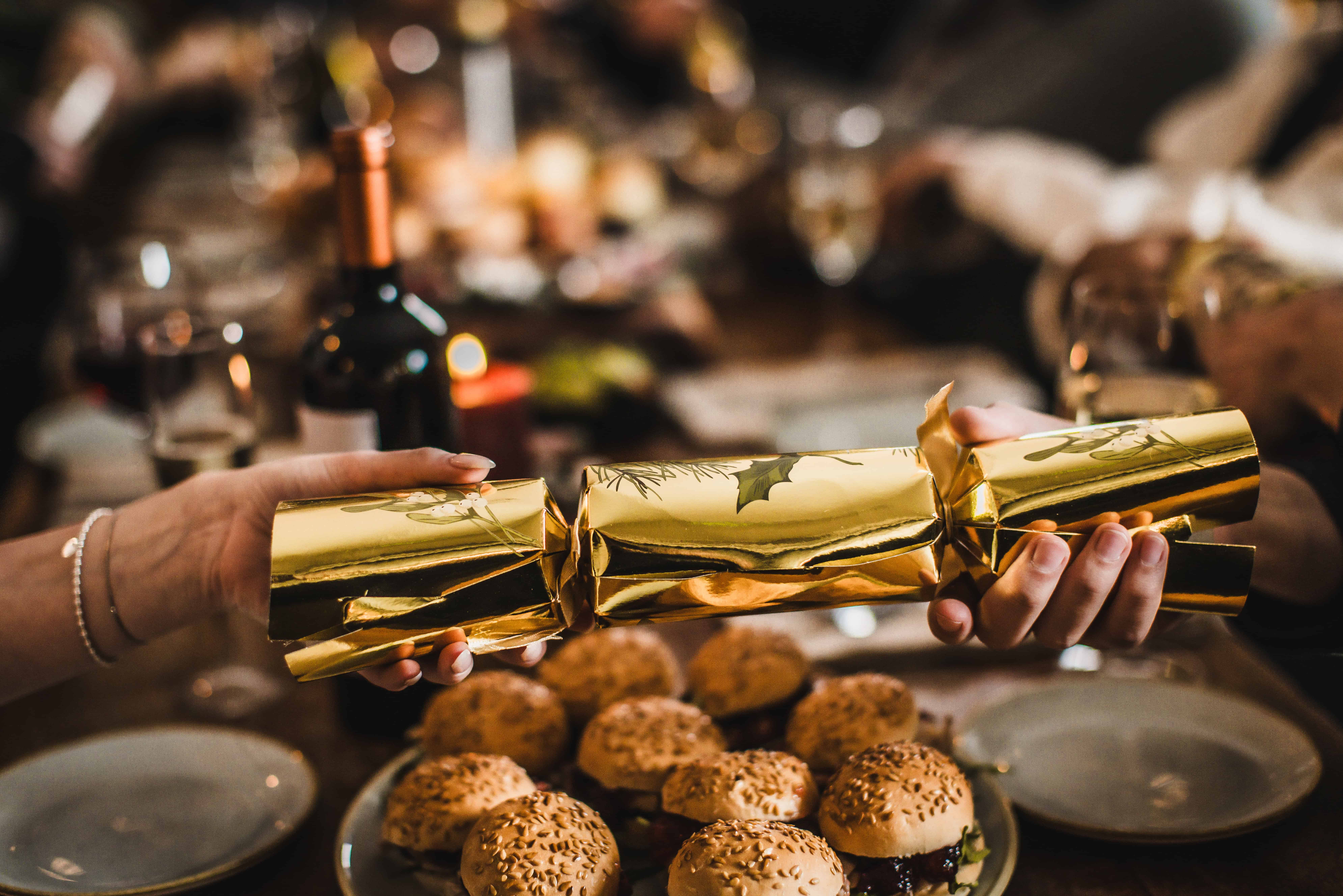 Person holding a gold-wrapped Christmas cracker at St Christopher's Pub.