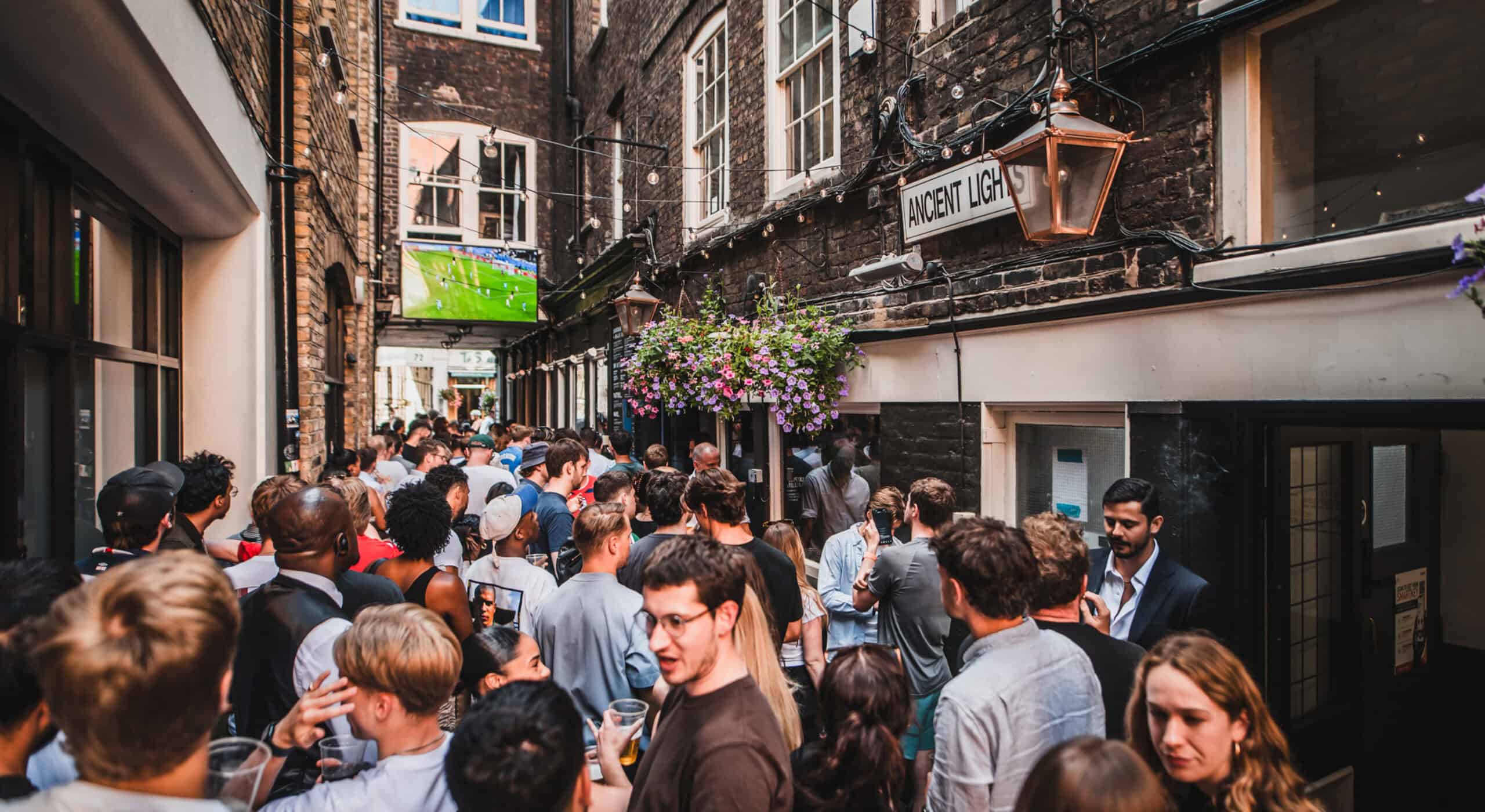 Crowd gathered outside St Christopher's Pub in a busy London street.