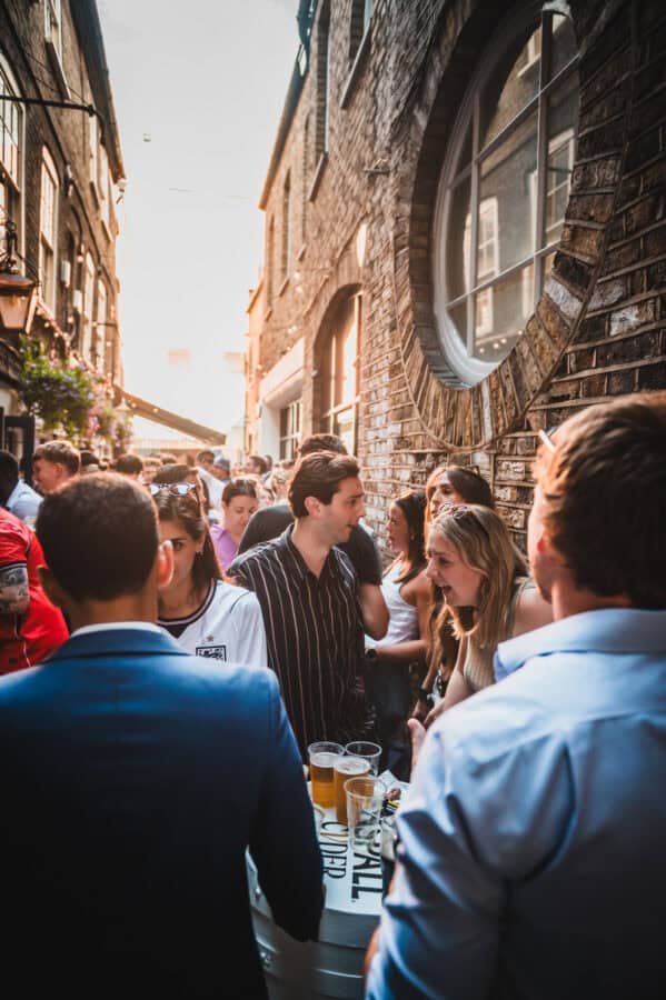 Crowd of people enjoying drinks outside St Christopher's Pub in London.