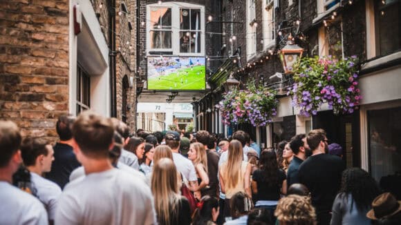 Crowd enjoying outdoor event at St Christopher's Pub in a narrow alleyway.