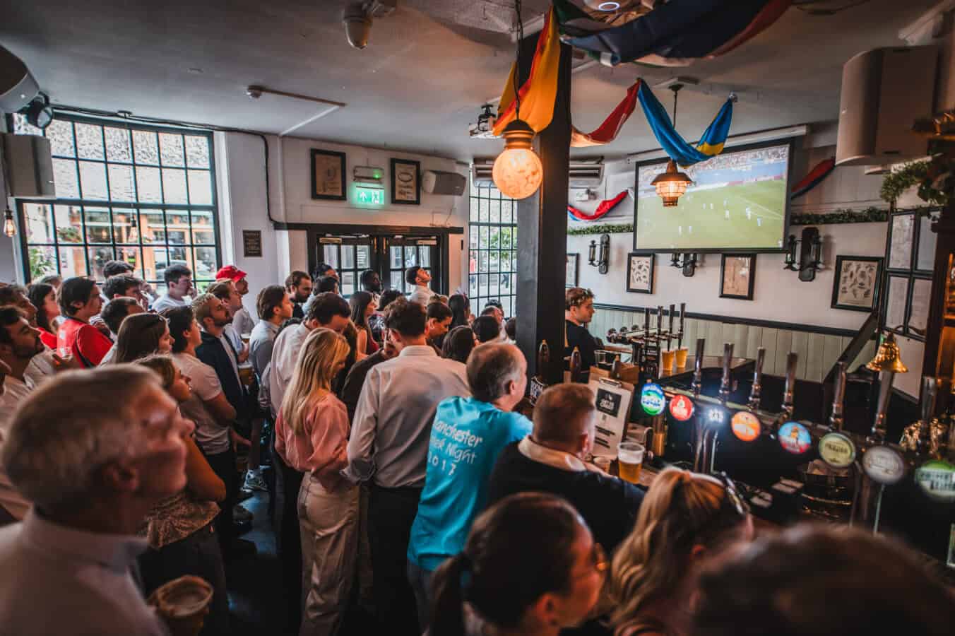 Crowd watching a football match on TV at St Christopher's Pub.