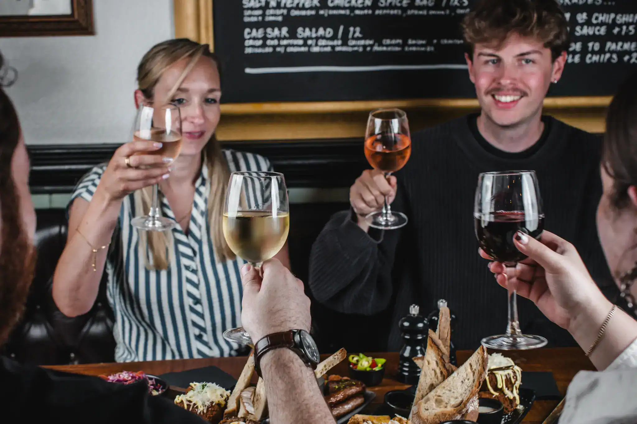 Group of friends raising glasses of wine and champagne at St Christopher's Pub.