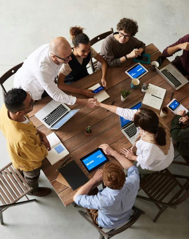 TeamForce Solutions marketing team collaborating around a table with laptops and tablets, driving digital growth for Hurst businesses.