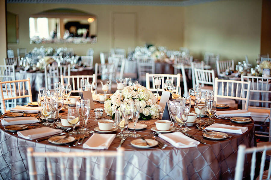 Wedding reception tables with floral centerpieces, elegant place settings, and banquet hall decor.