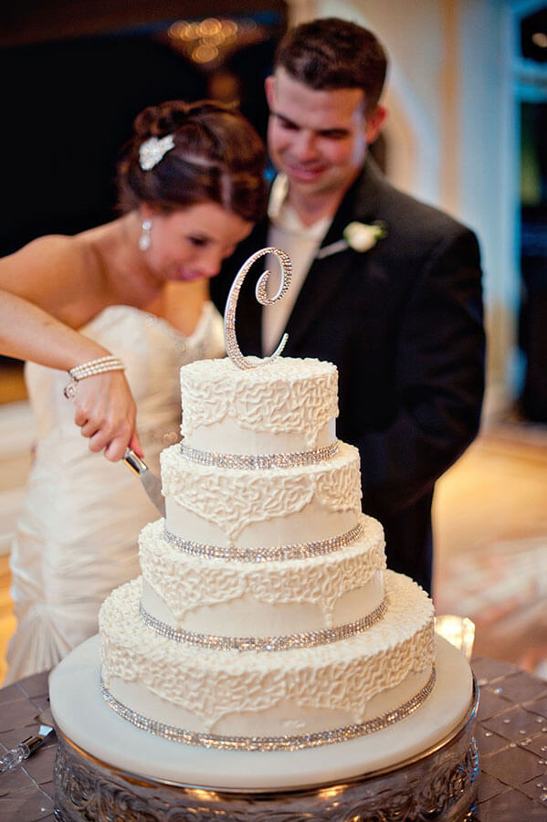 Bride and groom cut an elegant tiered wedding cake during their reception celebration.