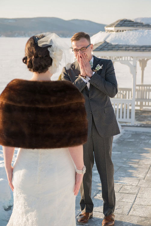 Groom’s emotional first look with his bride during a beautiful winter wedding by the lake.