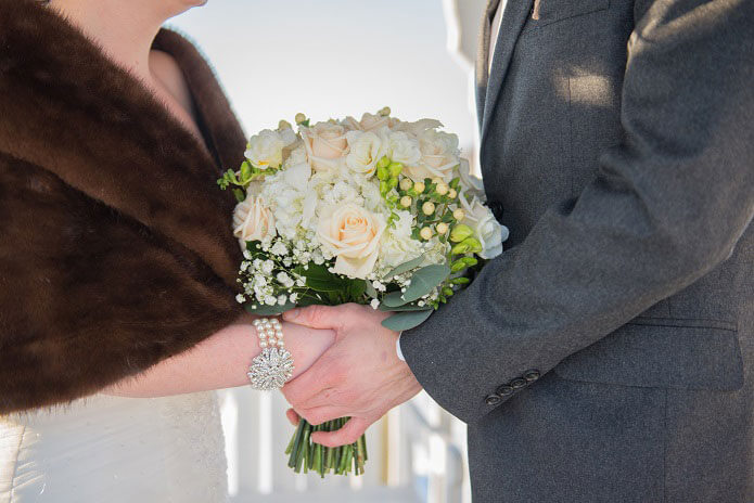 Joyous Moment Candlewood Inn winter wedding bouquet with bride and groom holding hands.