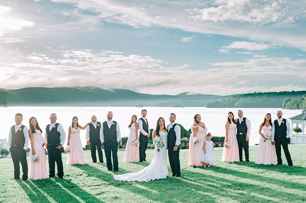 Wedding party poses by the lake with stunning views and elegant outdoor wedding attire.