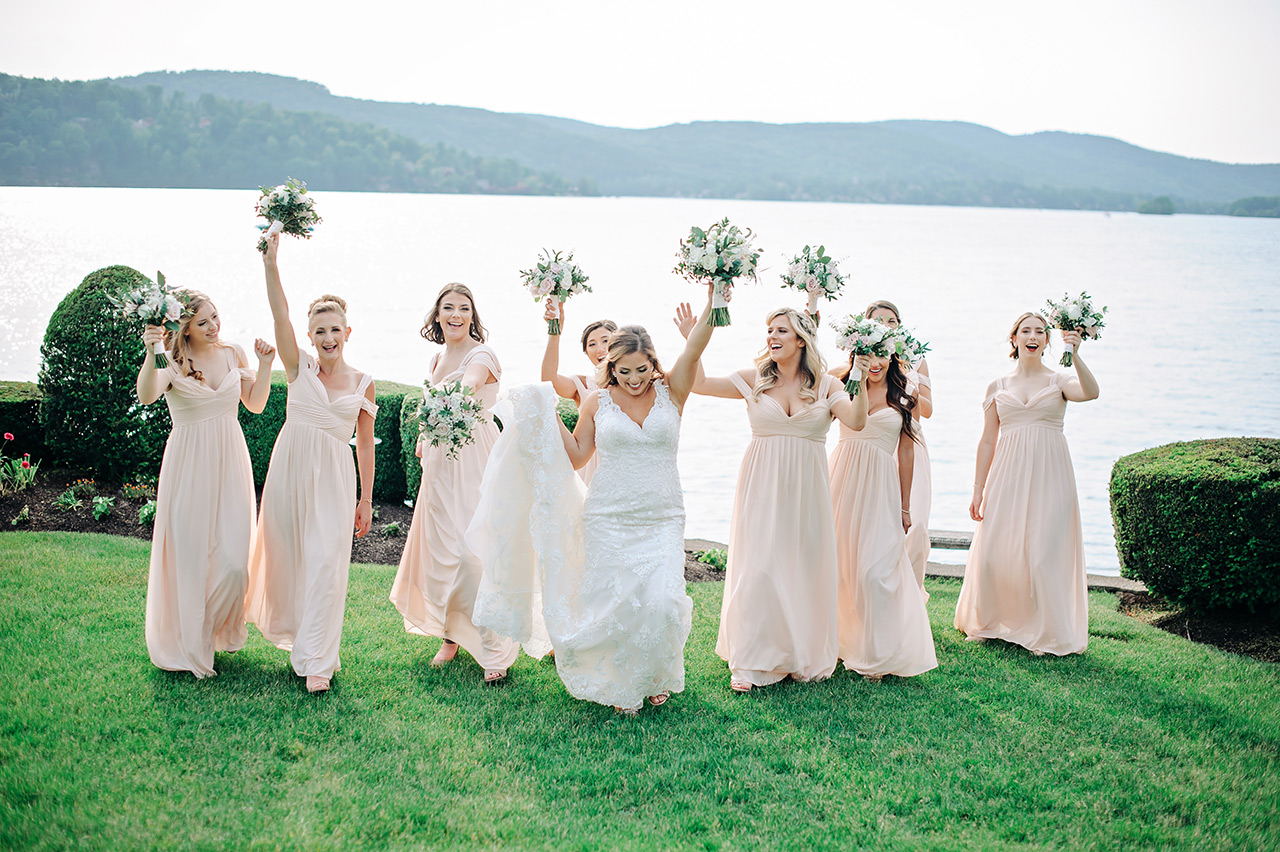 Bride and bridesmaids celebrate by the lake during a wedding at Candlewood Inn.