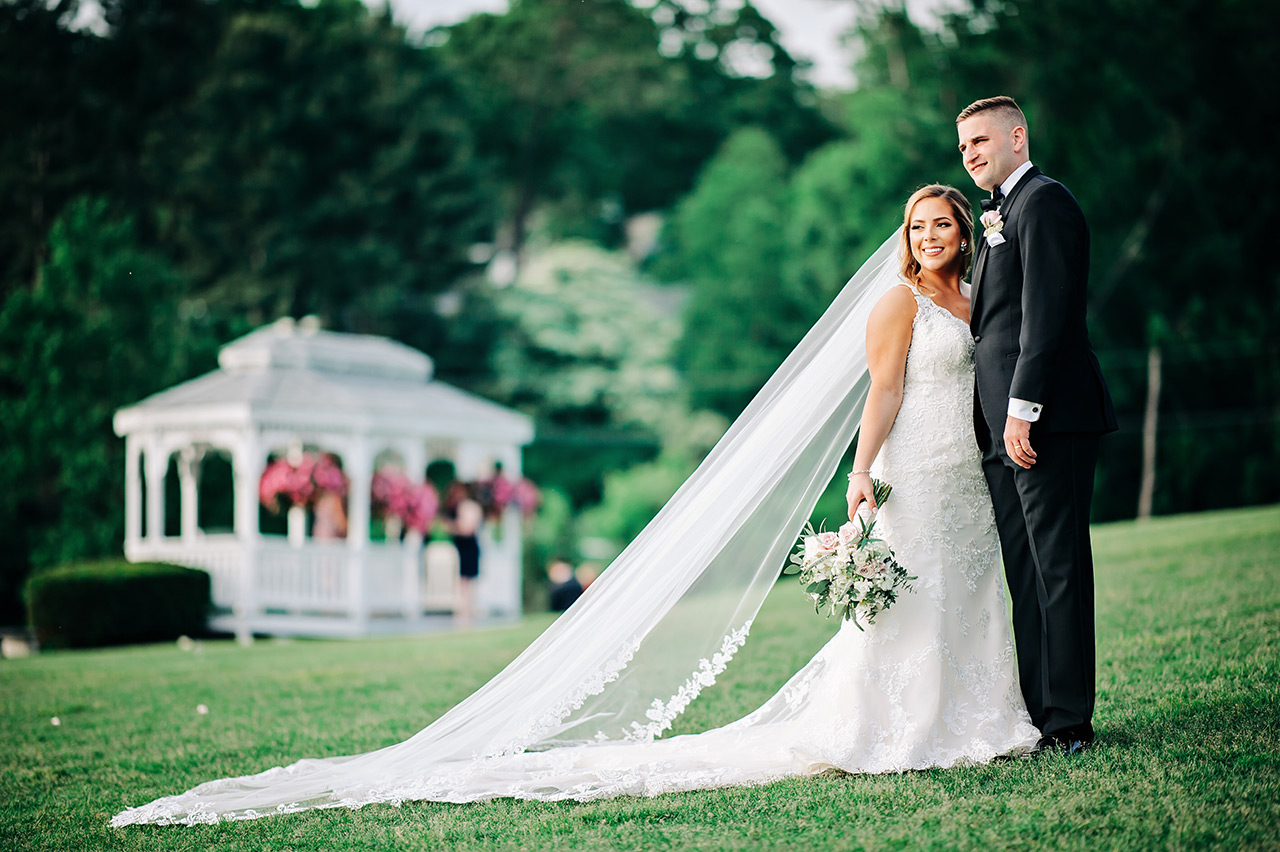 Bride and groom pose on the lawn with a gazebo backdrop at Candlewood Inn.