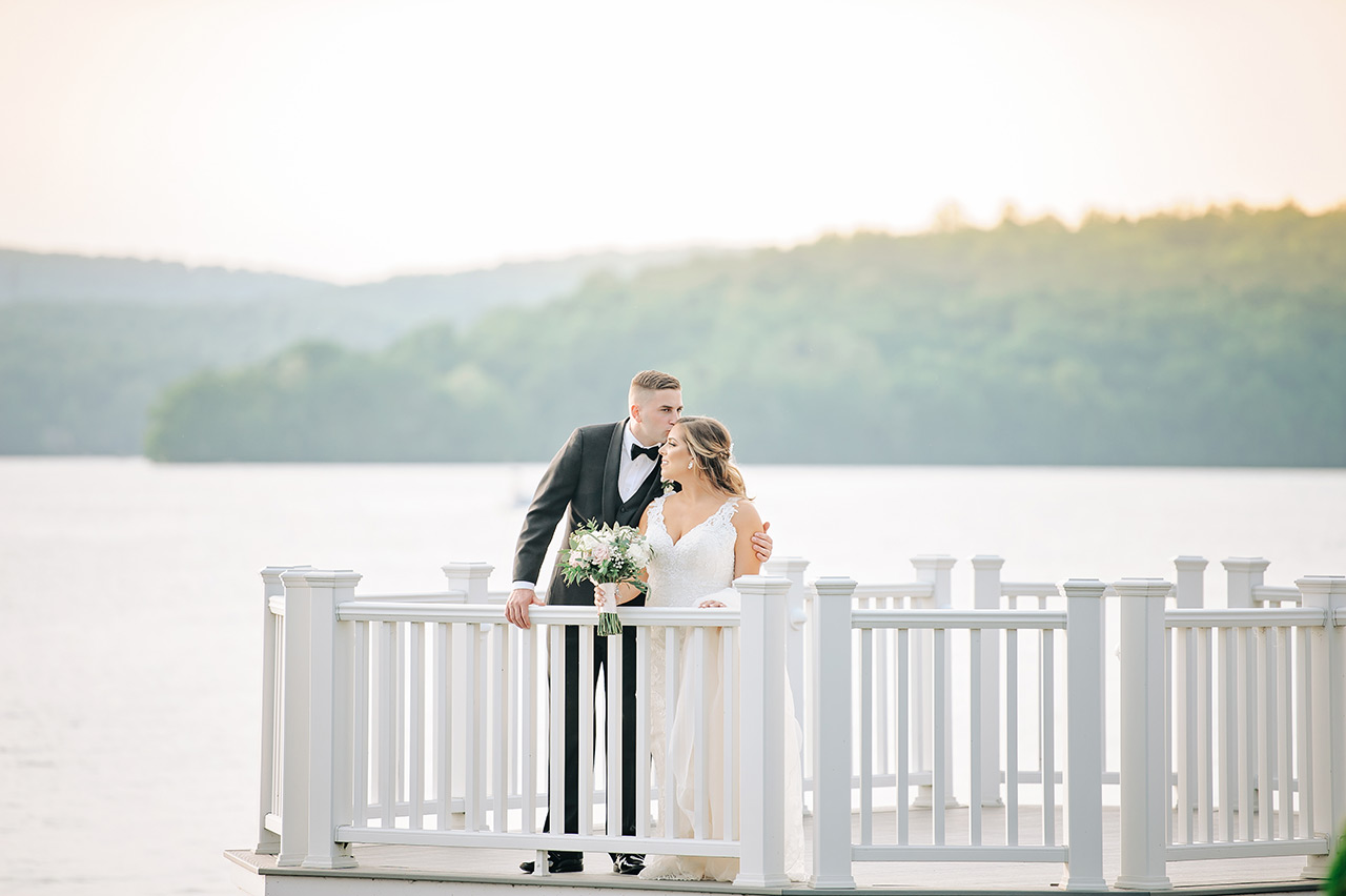 Bride and groom share a lakeside wedding portrait on the Candlewood Inn waterfront deck.
