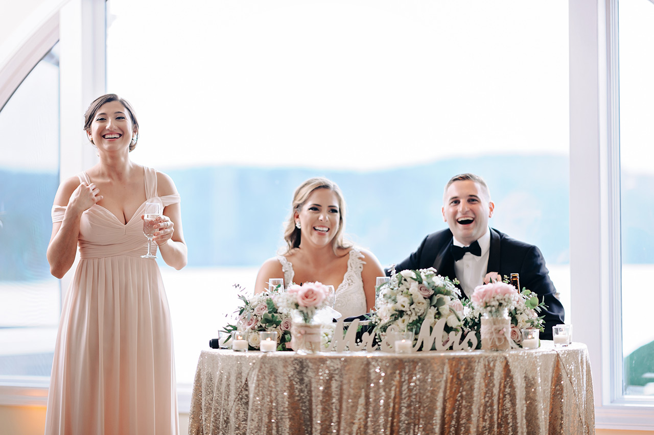 Wedding reception speech at the sweetheart table as guests celebrate the newly married couple.