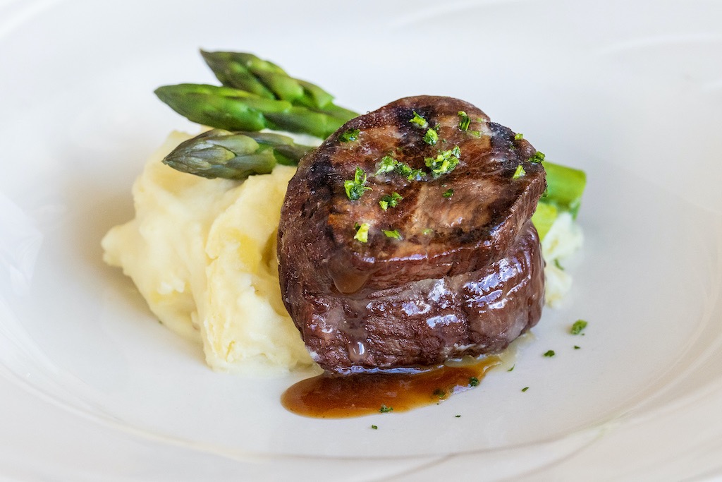 Filet mignon served with creamy mashed potatoes, asparagus, and a rich savory glaze.