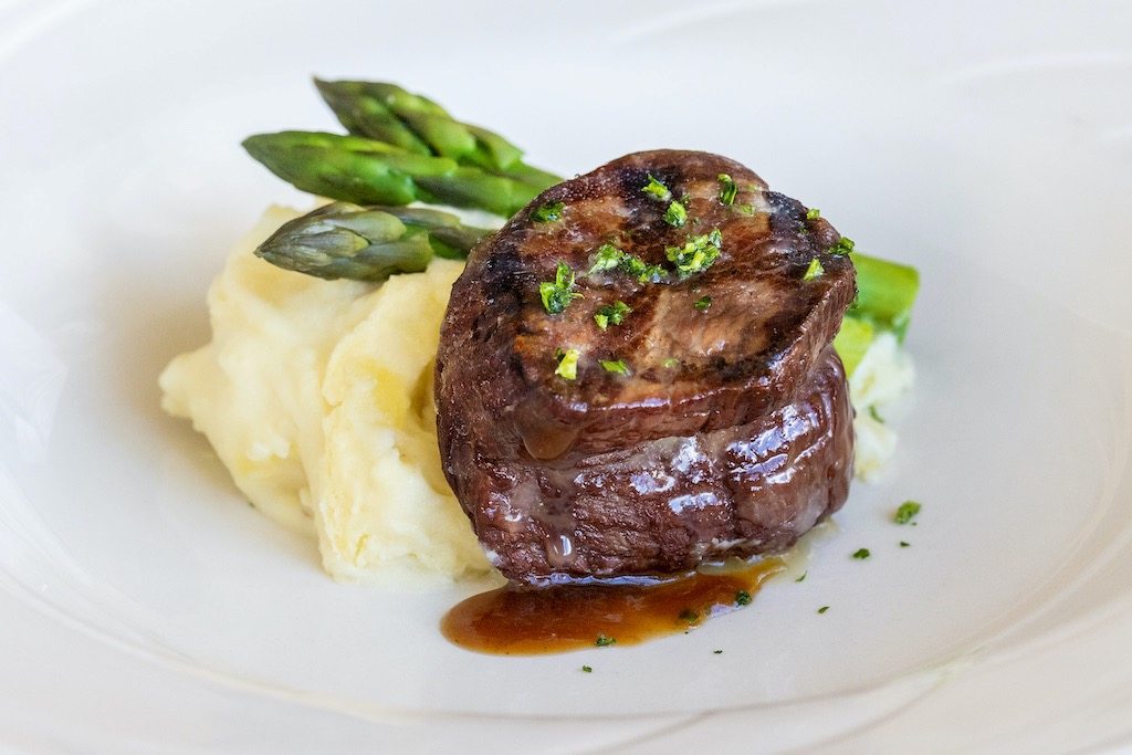 Filet mignon served with creamy mashed potatoes, asparagus, and a rich savory glaze.