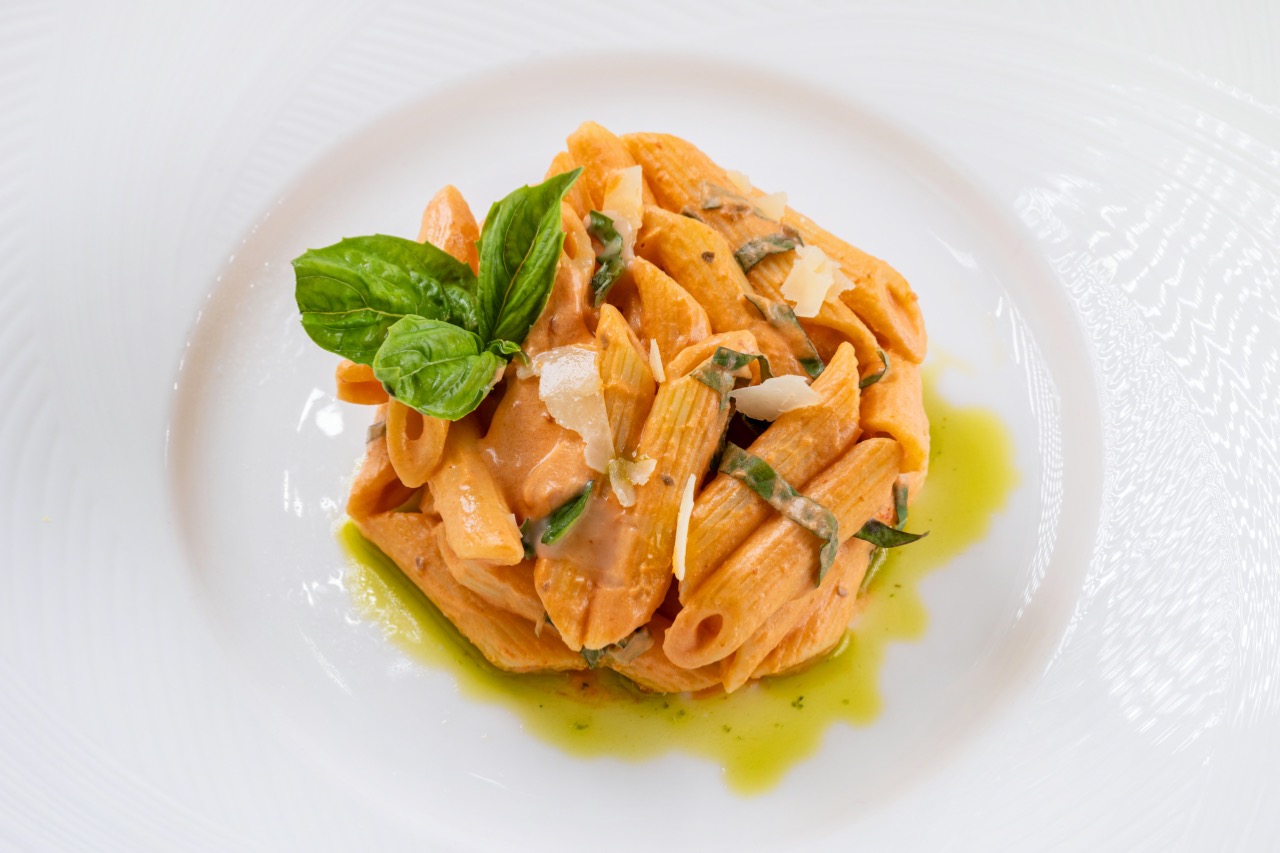 Penne alla vodka pasta in creamy tomato sauce, topped with basil and parmesan shavings.