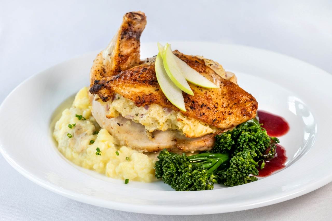 Stuffed chicken breast with mashed potatoes, broccolini, and a savory fruit glaze.