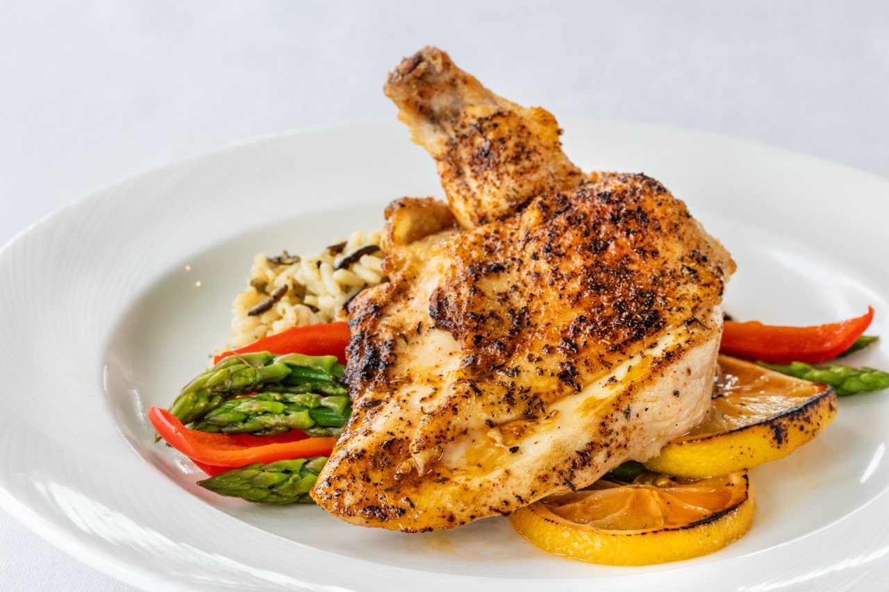 Grilled lemon chicken with wild rice, asparagus, roasted peppers, and charred citrus.