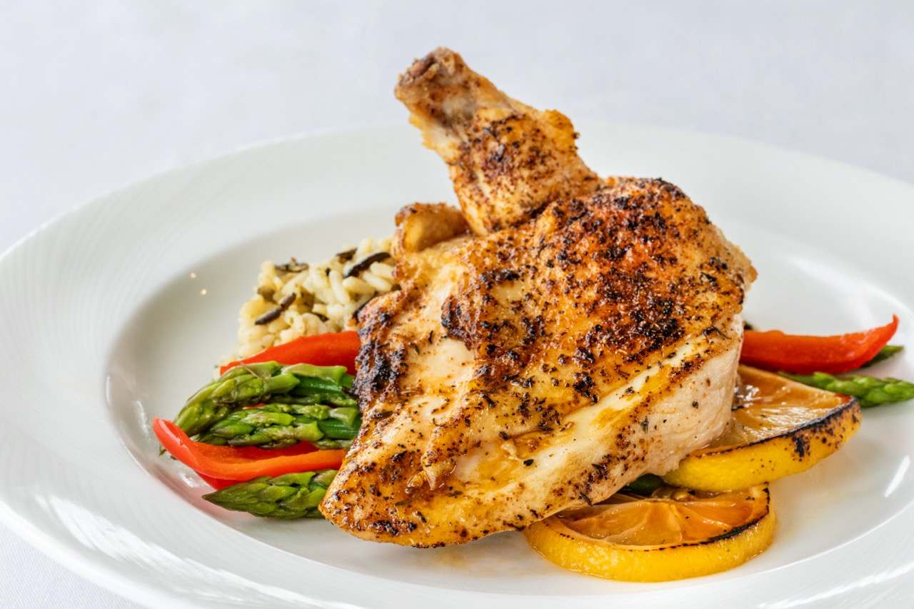 Grilled lemon chicken with wild rice, asparagus, roasted peppers, and charred citrus.