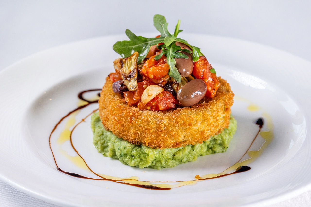 Crispy eggplant Provençal on pea purée, topped with roasted vegetables, olives, and arugula.