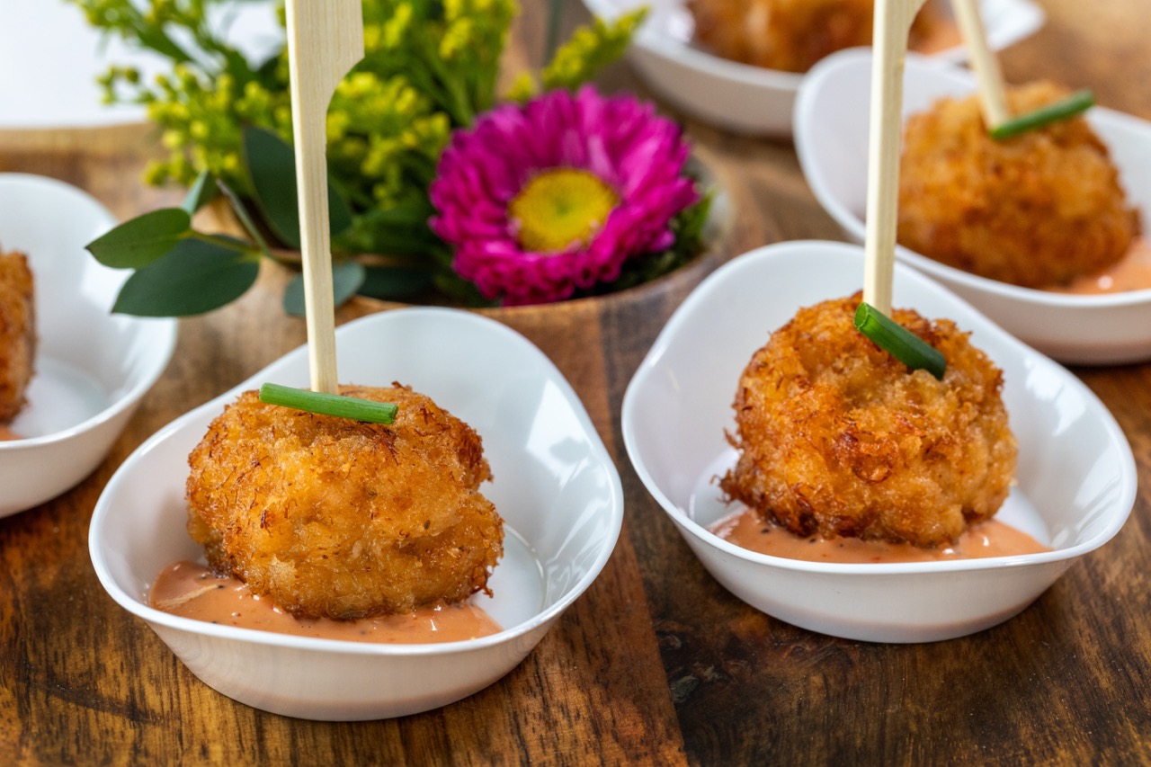 Golden crab cake appetizer served with creamy sauce in individual tasting bowls.