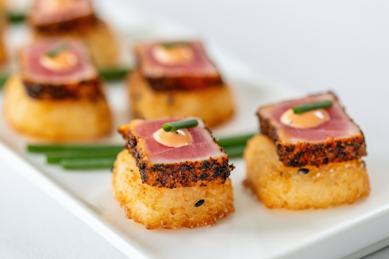 Spicy tuna appetizer with seared tuna, crispy rice, and spicy sauce garnish.