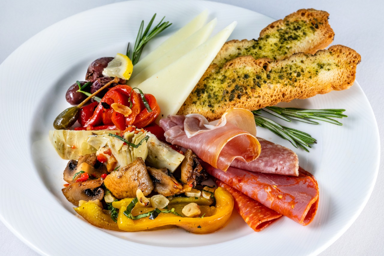 Antipasto Salad with cured meats, cheese, olives, vegetables, and garlic crostini on a platter.