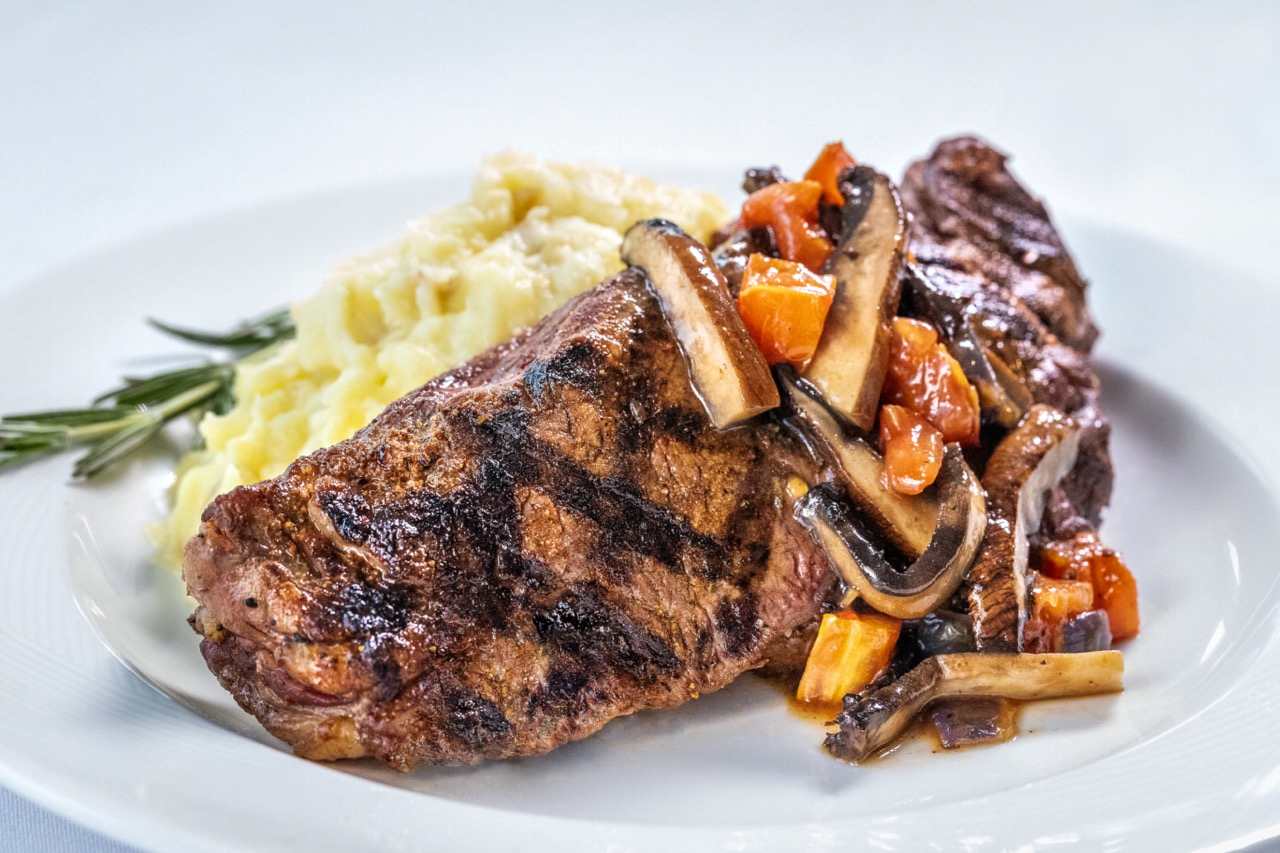 Grilled New York strip steak with mashed potatoes and sautéed mushrooms and vegetables.