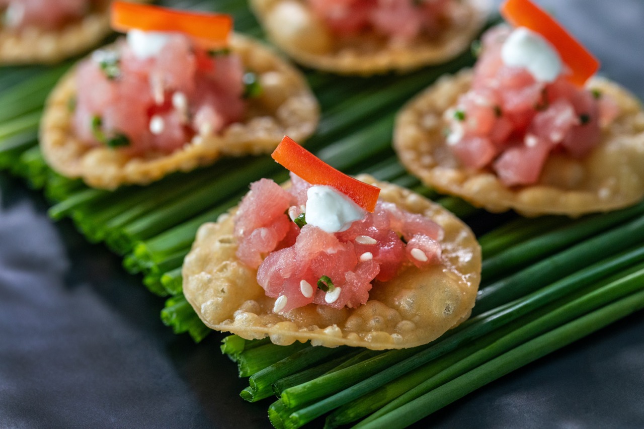 Tuna tartare served on crispy wonton chips with sesame seeds and spicy cream.