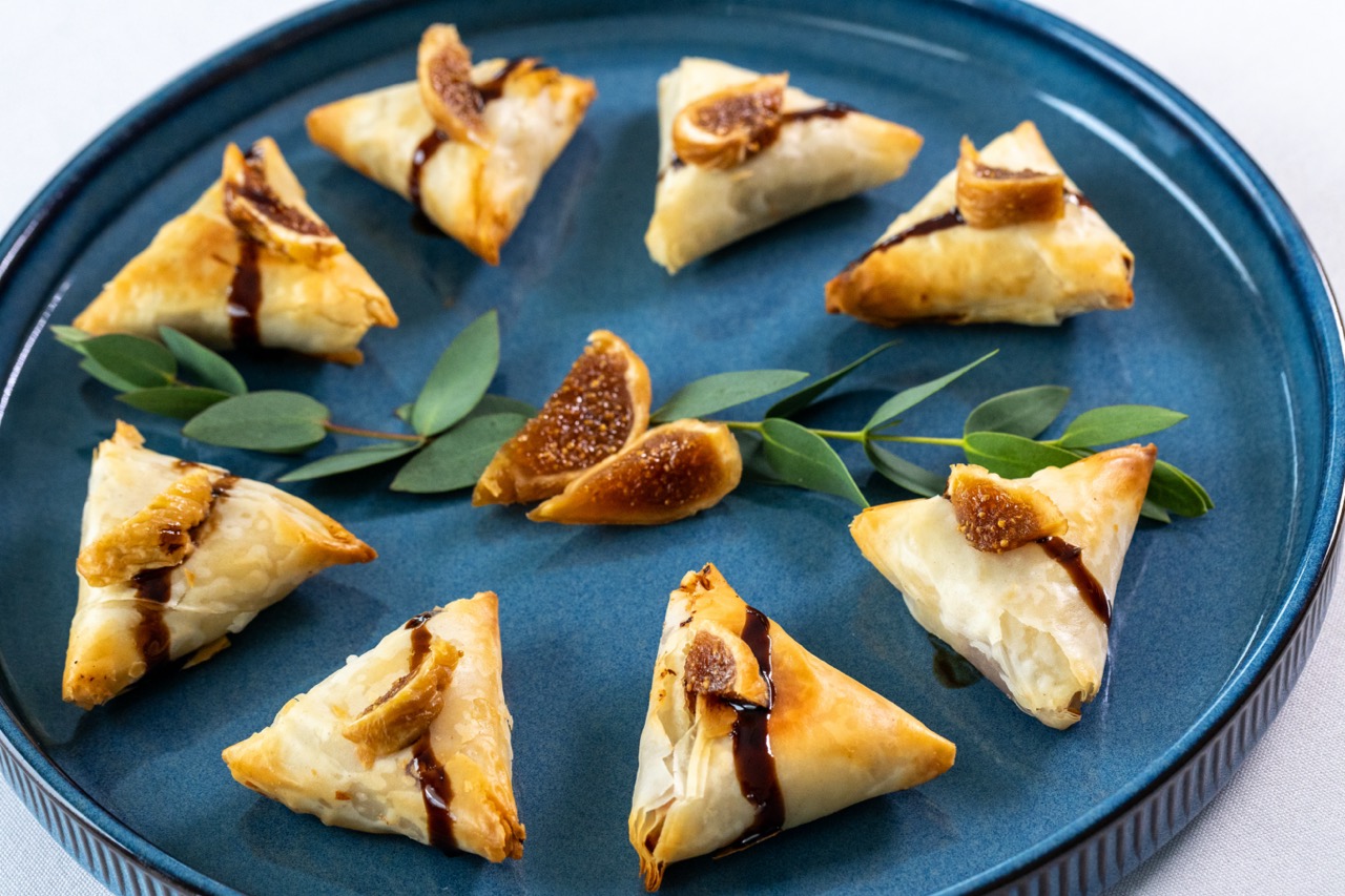 Fig and goat cheese bites in flaky pastry topped with fresh figs and balsamic drizzle.