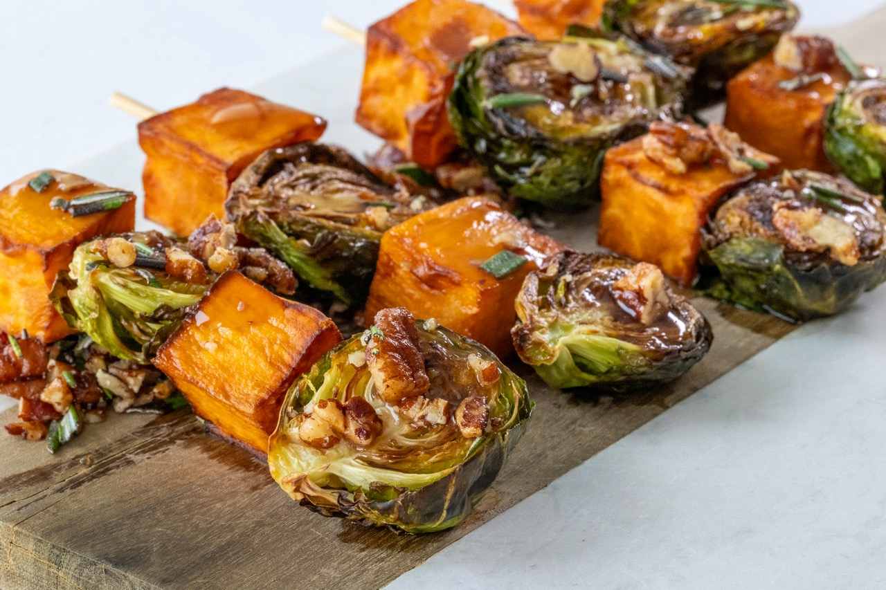 Roasted sweet potato and Brussels sprout skewers topped with pecans and balsamic glaze.