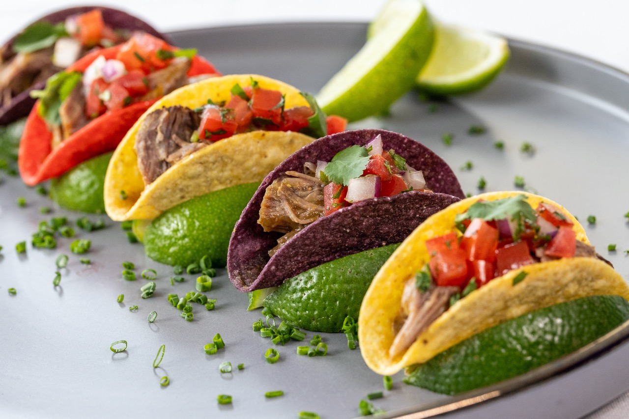 Short Rib Taco with pico de gallo, lime wedges, and colorful corn tortillas.
