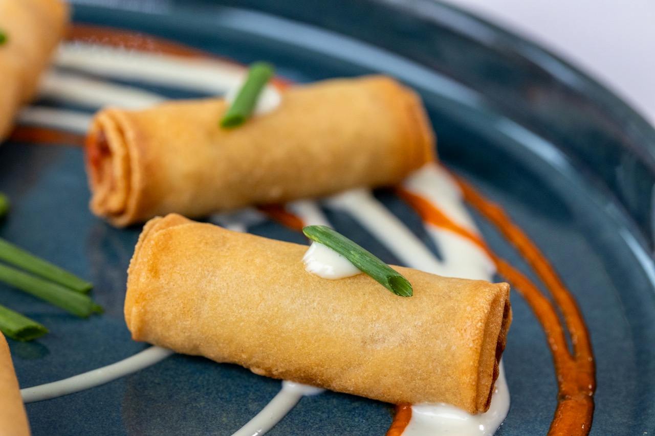 Buffalo chicken spring rolls served crispy with creamy ranch and spicy buffalo drizzle.