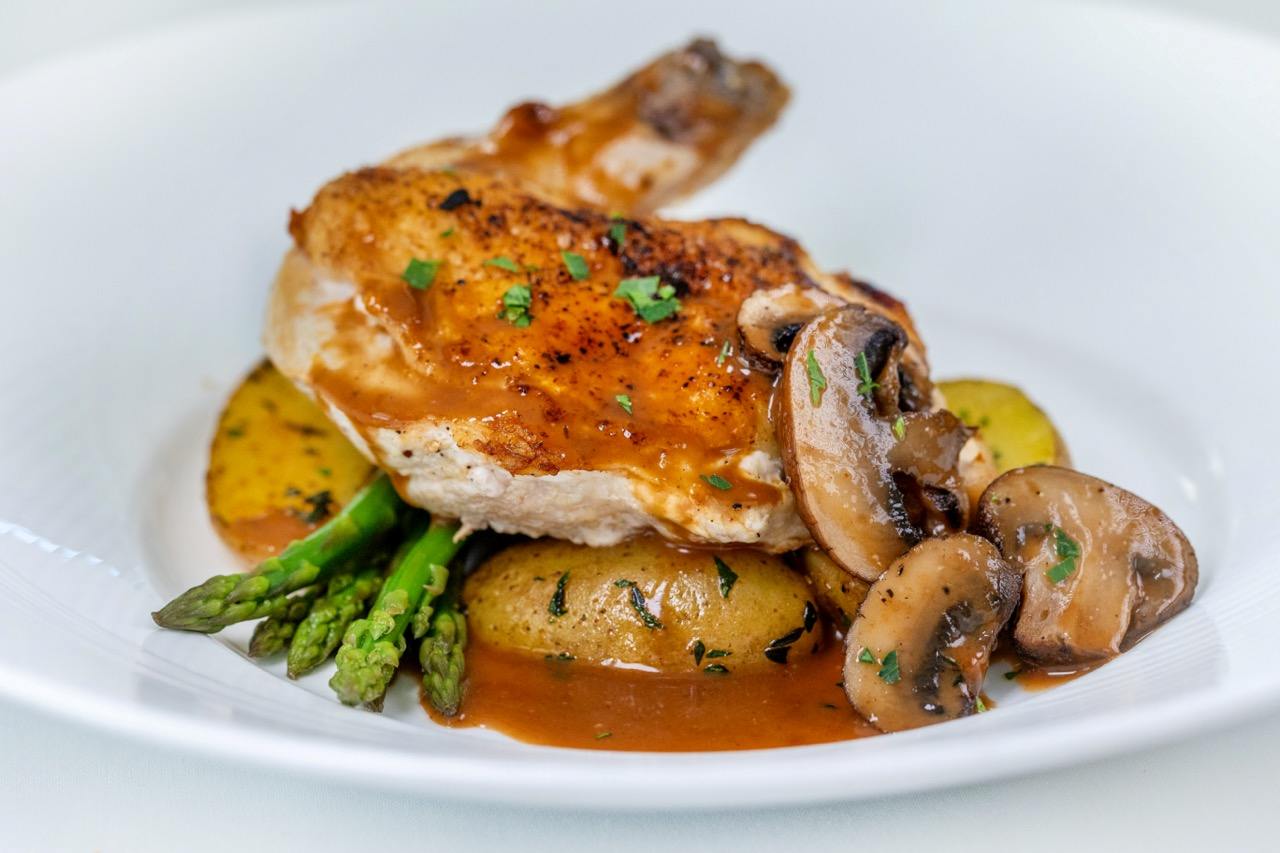 Chicken Marsala served with roasted potatoes, asparagus, and sautéed mushrooms in a rich sauce.