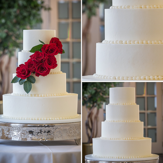 Four-tier white wedding cake with red rose cascade and elegant pearl borders.