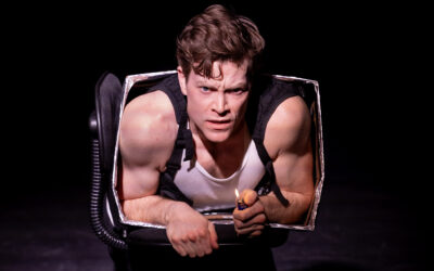 Intense male performer emerging from a theatrical prop, showcasing stagecraft, acting, and performance art for entertainment and theater productions.
