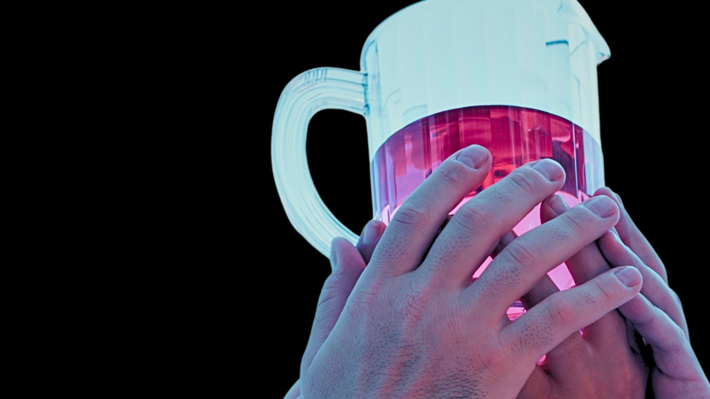 Close-up of a hand holding a glass beaker filled with pink liquid, used in scientific experiments and educational demonstrations.