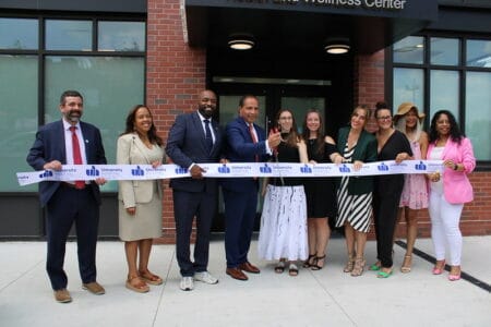 Ten people at the ribbon cutting outside the new Health and Wellness Center