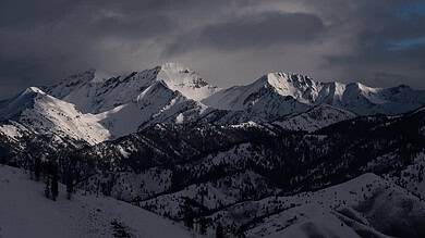 Bright snow-covered mountain peaks under a moody cloudy sky, showcasing winter mountain scenery and outdoor winter landscapes.