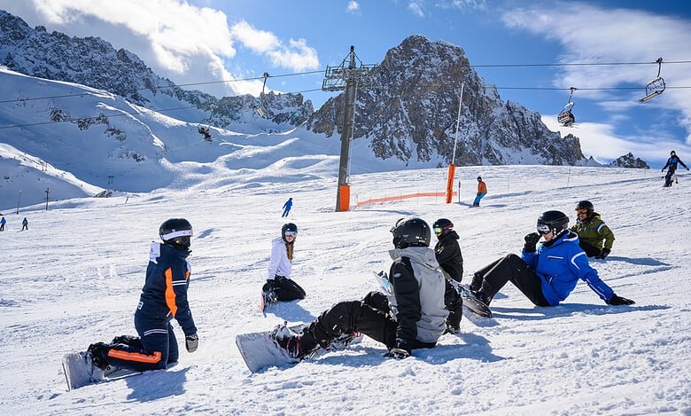 Kids snowboarding lesson on winter snowy mountain slope with ski lift and mountain backdrop, winter sports, snow activities, outdoor recreation, snow sports adventure, winter outdoor fun, skier training, learning to snowboard, mountain skiing, winter holiday activities.